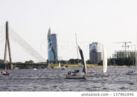 Riga, Latvia - June 30, 2024: Sailboats race across open water in a coastal regatta. Riga, Latvia - June 30, 2024: Sailboats race across open water in a coastal regatta. 137962846