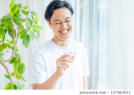 一名男子手拿一杯水 137963031