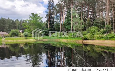 A calm pond sits in the middle of a green spring park. A feeling of balance and quiet relaxation. 137963108