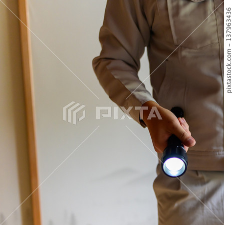 一名身穿工作服的男子拿著手電筒。 137963436