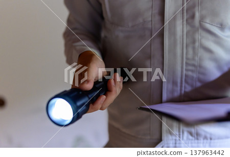 一名身穿工作服的男子正在用手電筒和文件檢查。 137963442