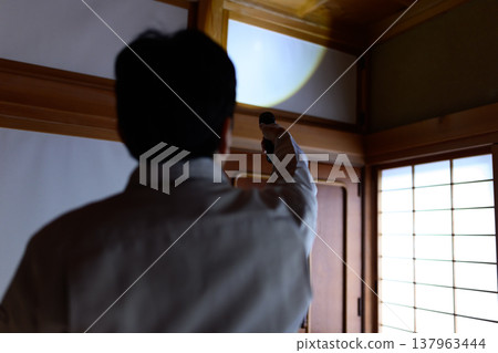 一名工人在昏暗的日式房間安裝天花板照明設備。 137963444