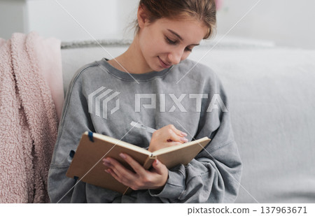 Pretty Girl Writes A Recipe In Notebook In The Kitchen 137963671