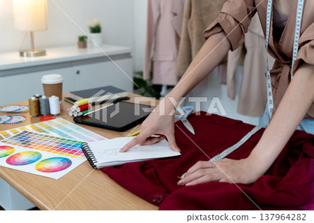 A fashion designer is designing a dress on a tailor 137964282