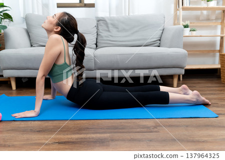 young woman exercising in lying yoga position to stretch young woman exercising in lying yoga position to stretch 137964325