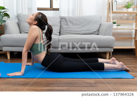 young woman exercising in lying yoga position to stretch 137964326