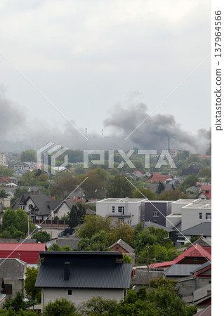 Thick black smoke rising over a residential area after an explosion or fire. Concept of war in Ukraine, missile strike consequences, and urban destruction. Aerial view of a city under attack Thick black smoke rising over a residential area after an explosion or fire. Concept of war in Ukraine, missile strike consequences, and urban destruction. Aerial view of a city under attack 137964566