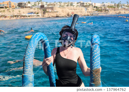 A woman overcomes her fear as she puts on a snorkel mask for the first time and dives into the water 137964762