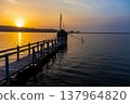 A view of Lake Togo and the setting sun, with a hut for observing the four-pronged net fishing method floating at the end of the pier. 137964820