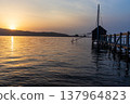A view of Lake Togo and the setting sun, with a hut for observing the four-pronged net fishing method floating at the end of the pier. 137964823