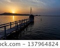 A view of Lake Togo and the setting sun, with a hut for observing the four-pronged net fishing method floating at the end of the pier. 137964824