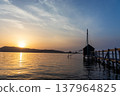 A view of Lake Togo and the setting sun, with a hut for observing the four-pronged net fishing method floating at the end of the pier. 137964825