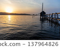 A view of Lake Togo and the setting sun, with a hut for observing the four-pronged net fishing method floating at the end of the pier. 137964826