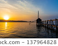 A view of Lake Togo and the setting sun, with a hut for observing the four-pronged net fishing method floating at the end of the pier. 137964828