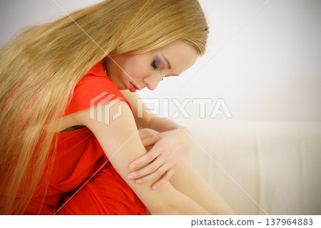 Sad elegant woman sitting on sofa Sad elegant woman sitting on sofa 137964883
