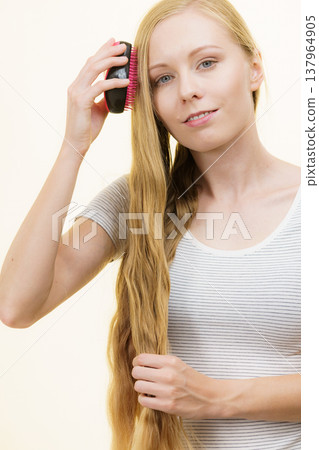 Blonde girl brushing her long hair 137964905