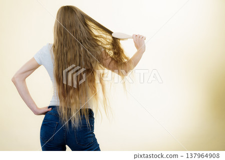 Blonde girl brushing her long hair Blonde girl brushing her long hair 137964908