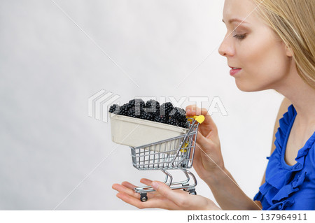 Girl holds blackberry fruits in shopping cart Girl holds blackberry fruits in shopping cart 137964911
