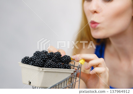 Girl holds blackberry fruits in shopping cart Girl holds blackberry fruits in shopping cart 137964912