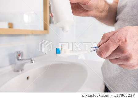 Person putting toothpaste on toothbrush Person putting toothpaste on toothbrush 137965227