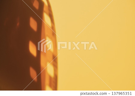 Film strip with sprocket holes illuminated creating warm nostalgic effect Film strip with sprocket holes illuminated creating warm nostalgic effect 137965351