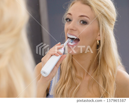 Woman using electric toothbrush Woman using electric toothbrush 137965387