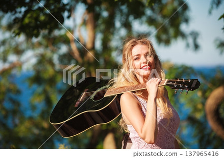 Blonde woman with acoustic guitar on seaside 137965416
