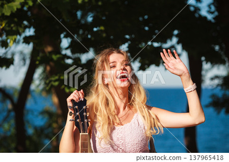 Blonde woman with acoustic guitar on seaside Blonde woman with acoustic guitar on seaside 137965418