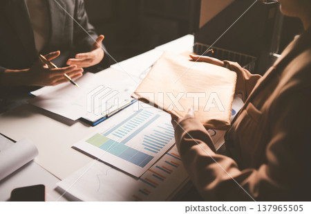 Two business people talk project strategy at office meeting room. Businessman discuss project planning with colleague at modern workplace while having conversation and advice on financial data report. Two business people talk project strategy at office meeting room. Businessman discuss project planning with colleague at modern workplace while having conversation and advice on financial data report. 137965505