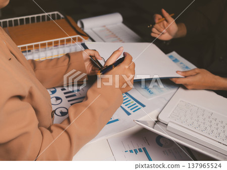 Two business people talk project strategy at office meeting room. Businessman discuss project planning with colleague at modern workplace while having conversation and advice on financial data report. 137965524