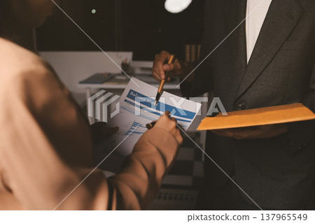 Two business people talk project strategy at office meeting room. Businessman discuss project planning with colleague at modern workplace while having conversation and advice on financial data report. 137965549