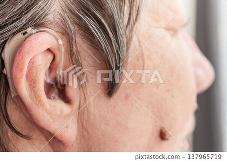 Closeup senior woman using hearing aid Closeup senior woman using hearing aid 137965719