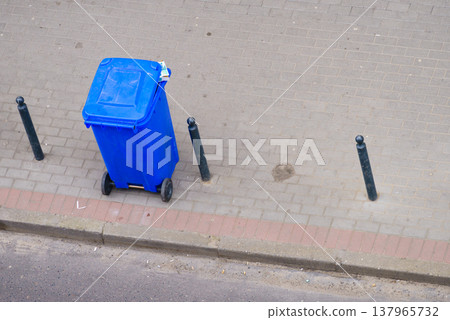 Blue trash can on street pavement Blue trash can on street pavement 137965732