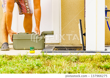 Man emptying caravan tank toilet cassette in dump station. Man emptying caravan tank toilet cassette in dump station. 137966275