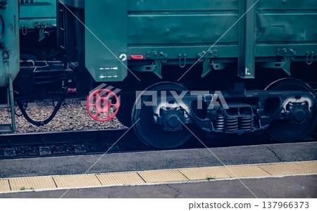 Close-up of a train wheel and red valve on a railway track. Close-up of a train wheel and red valve on a railway track. 137966373