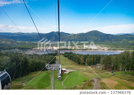 Mangekok, Russia-18.08.2024: .Cable cars over lush green landscape and forested hills in Mangerok. Mangekok, Russia-18.08.2024: .Cable cars over lush green landscape and forested hills in Mangerok. 137966376