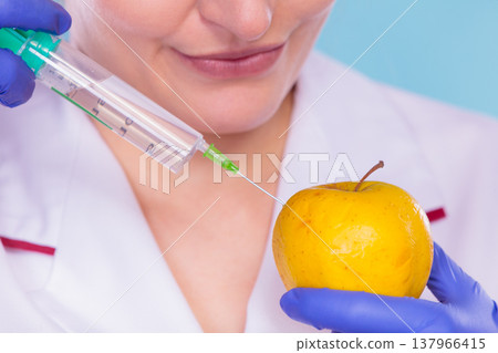 Scientist doctor injecting apple. GM Food. 137966415