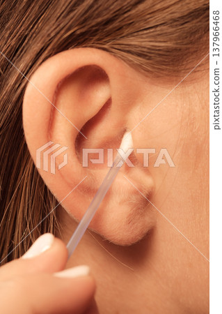 Woman cleaning ear with cotton swabs closeup Woman cleaning ear with cotton swabs closeup 137966468