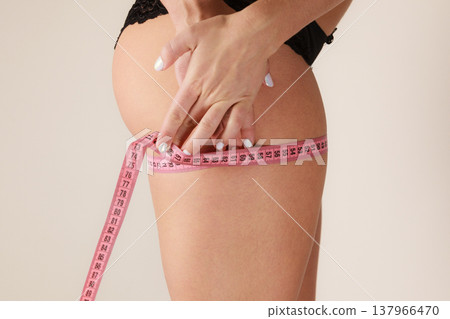 Woman measuring her thigh closeup Woman measuring her thigh closeup 137966470