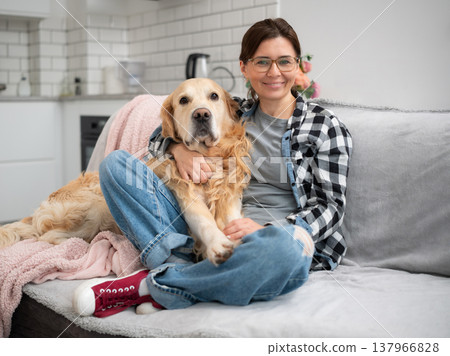 Happy Girl Hugs Adorable Golden Retriever Dog At Home While Looking At The Camera Happy Girl Hugs Adorable Golden Retriever Dog At Home While Looking At The Camera 137966828