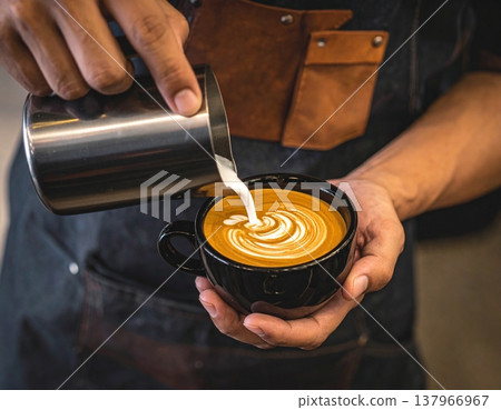 A skilled barista carefully pours steamed milk into a dark ceramic cup A skilled barista carefully pours steamed milk into a dark ceramic cup 137966967