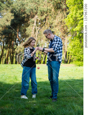 Father And Daughter Play With Yo-Yo Ball In Summer Park Father And Daughter Play With Yo-Yo Ball In Summer Park 137967200