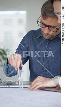 Architects collaborating on architectural plans. Designing modern building models. Drawing blueprints. Engineering innovative residential project solutions Architects collaborating on architectural plans. Designing modern building models. Drawing blueprints. Engineering innovative residential project solutions 137968073