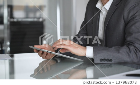 Businessman in a modern office using a digital tablet, managing data and corporate tasks, embracing mobile technology for productivity and efficient communication during a meeting, close up. Businessman in a modern office using a digital tablet, managing data and corporate tasks, embracing mobile technology for productivity and efficient communication during a meeting, close up. 137968078