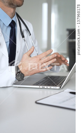 Doctor in white coat showing test results to patient on tablet during consultation. Medicine, healthcare and science concept Doctor in white coat showing test results to patient on tablet during consultation. Medicine, healthcare and science concept 137968178