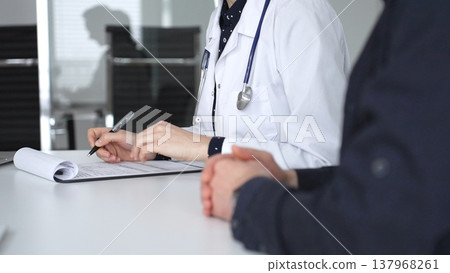 Experienced female doctor consulting patient man, providing medical advice and writing prescription during hospital appointment. Medicine, healthcare and science concept Experienced female doctor consulting patient man, providing medical advice and writing prescription during hospital appointment. Medicine, healthcare and science concept 137968261