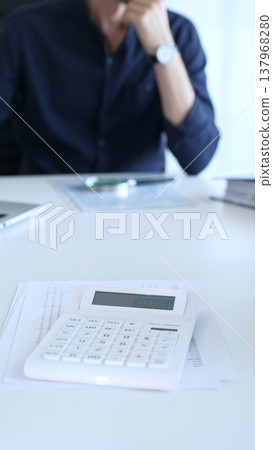 Businessman is having problems with finance, he's stressed and thinking about solutions, focusing on calculator and documents. Audit and taxes in business Businessman is having problems with finance, he's stressed and thinking about solutions, focusing on calculator and documents. Audit and taxes in business 137968280