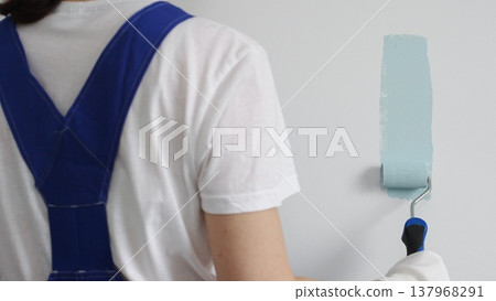 House painter rolling light blue paint on white wall, transforming interior space with smooth strokes and professional technique during home renovation project House painter rolling light blue paint on white wall, transforming interior space with smooth strokes and professional technique during home renovation project 137968291