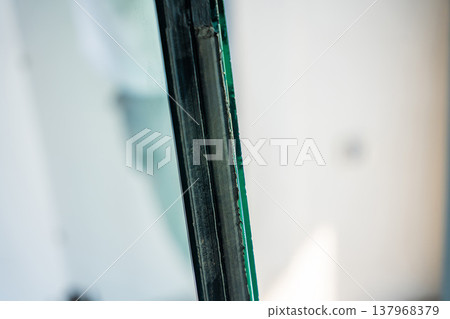 Edge detail of triple glazed window unit showing layered glass structure. Modern energy efficient window construction concept. Edge detail of triple glazed window unit showing layered glass structure. Modern energy efficient window construction concept. 137968379