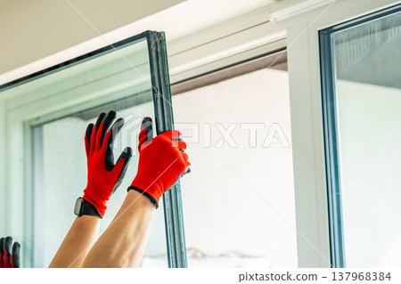 Removed triple glazed window glass unit leaning near frame after replacement in apartment. Broken insulated glass panel removal and window repair process concept. Removed triple glazed window glass unit leaning near frame after replacement in apartment. Broken insulated glass panel removal and window repair process concept. 137968384